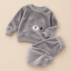Pyjama pilou pilou enfant chat moelleux deux pièces posé à plat sur fond beige, sans personne