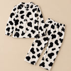 Ensemble pyjama deux pièces Ensemble pyjama femme et ado vache noir et blanc posé à plat sur fond beige, sans personne