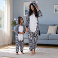 Combi pyjama zèbre noir et blanc adulte et enfant porté dans un intérieur chaleureux